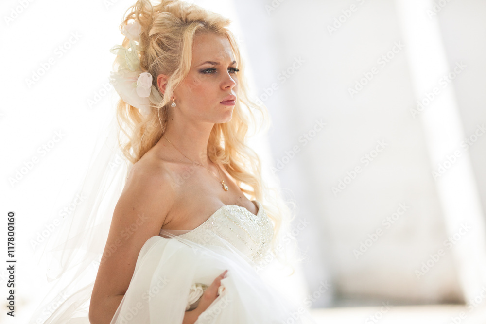 Curly bride looks serious standing in the white room Curly bride looks serious standing in the white room