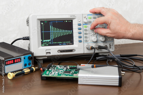 Fotografía The man's hand turning signal adjustment knob on the oscilloscope panel