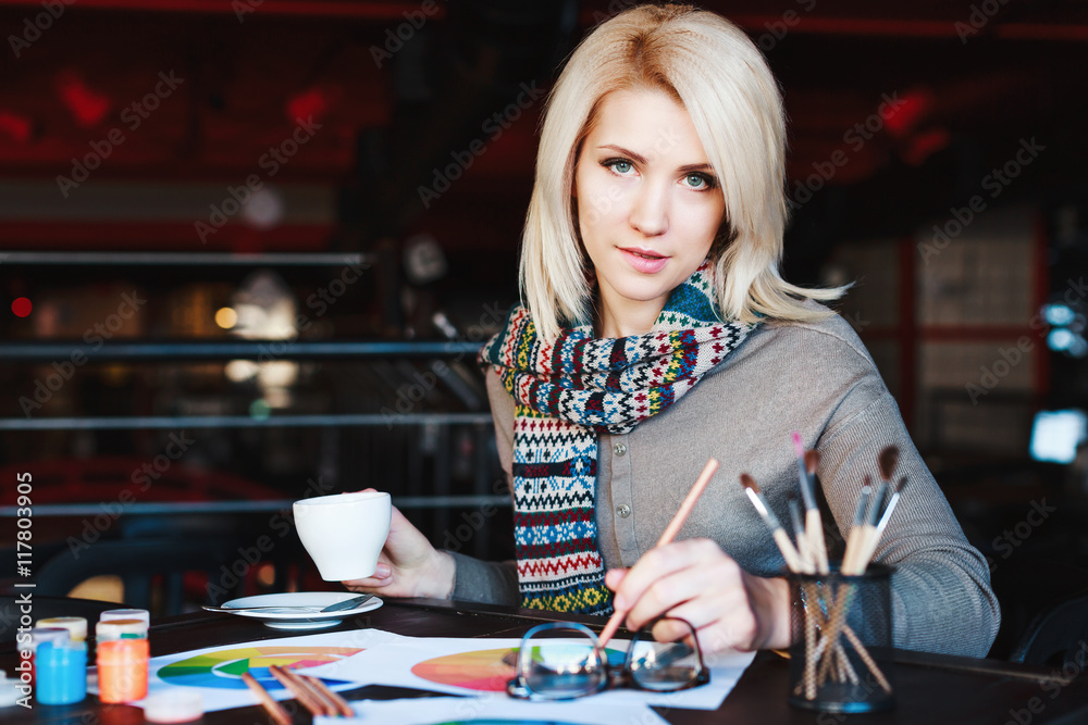 Fototapeta premium Girl sitting in cafe with cup of coffee and drawing