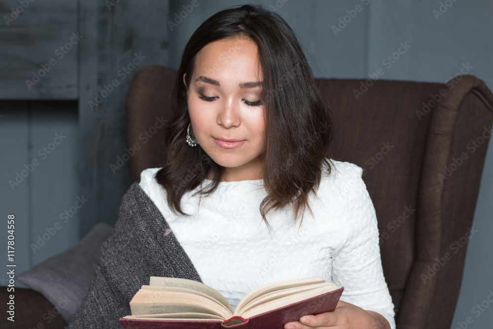 young,beautiful girl wrapped in warm plaid blanket reading book young,beautiful girl wrapped in warm plaid blanket reading book