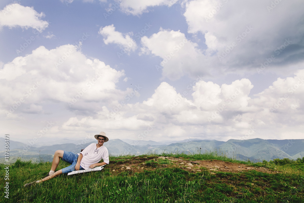 hipster traveler sitting at top of mountains with amazing view a hipster traveler sitting at top of mountains with amazing view a
