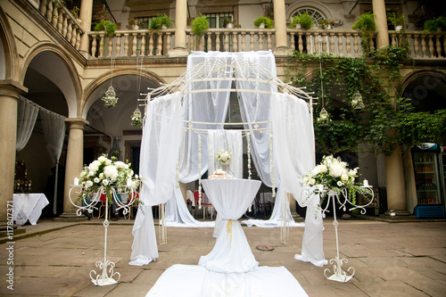 Wedding altar made of white laces stands in the Italian bakcyard photo