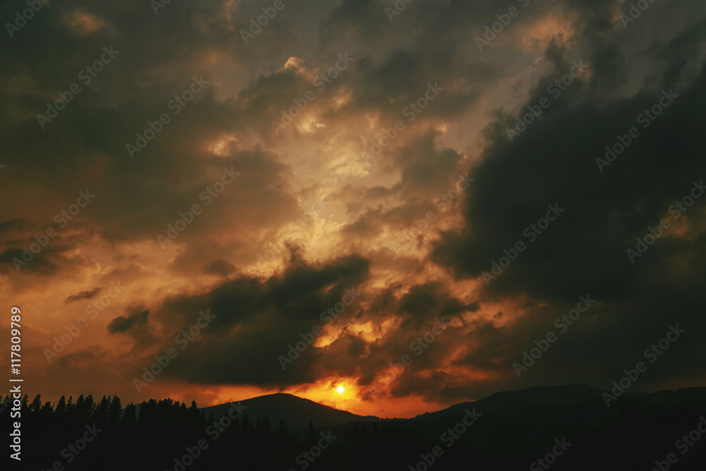 amazing sunset in mountains landscape, sun and clouds and woods