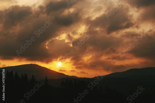 amazing sunset in mountains landscape, sun and clouds and woods