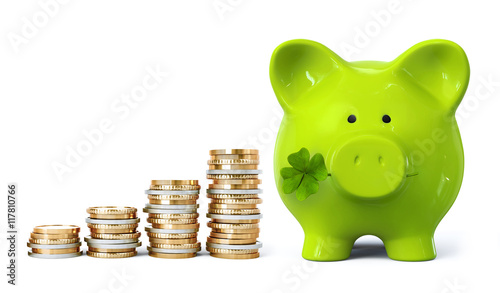 Green piggy bank with four leaf clover and coin stacks in ascending order photo