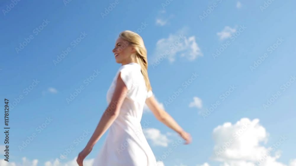 smiling young woman in white dress over blue sky smiling young woman in white dress over blue sky