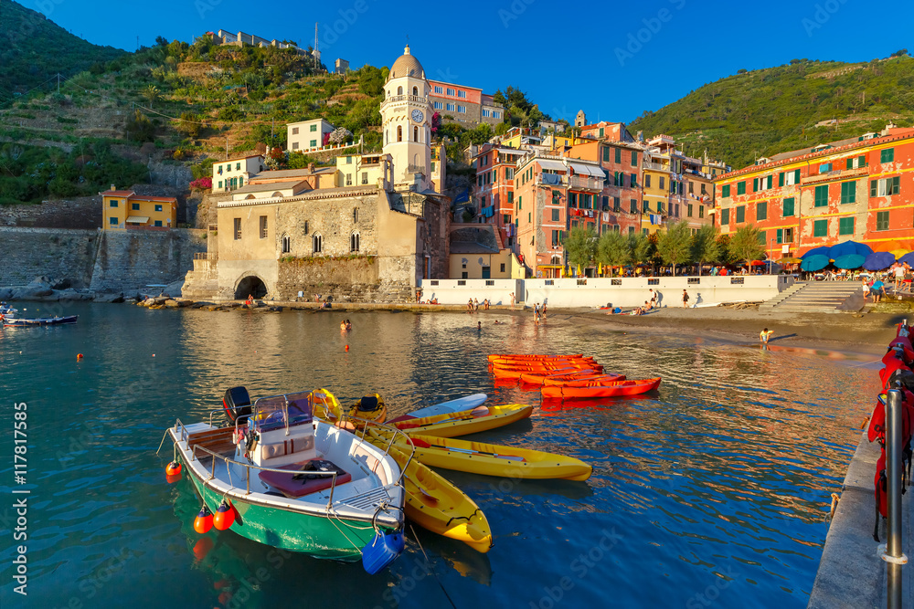 The colorful fishing boats and Santa Margherita di Antiochia Church in Vernazza harbour in Five lands, Cinque Terre National Park, Liguria, Italy.
