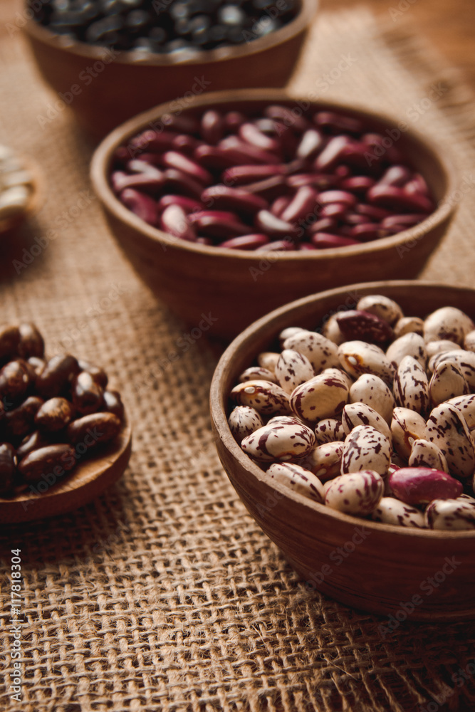 Beautiful multi-colored beans in ceramic bowls on a background of burlap Beautiful multi-colored beans in ceramic bowls on a background of burlap