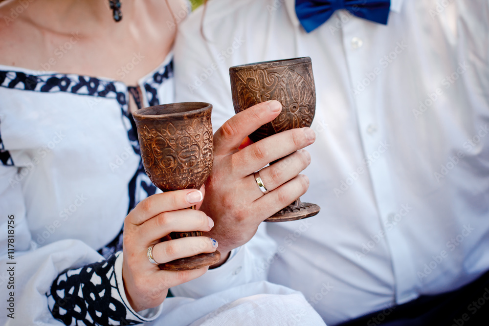 a pair of newlyweds holding vintage wooden glasses with champagne