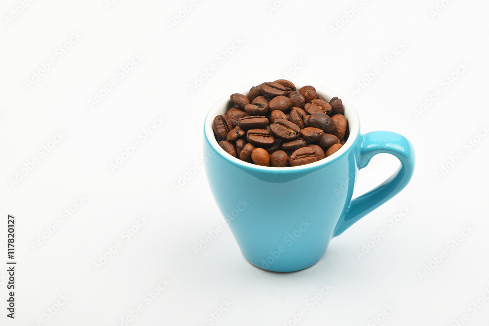 Blue espresso cup full of coffee beans over white Blue espresso cup full of coffee beans over white