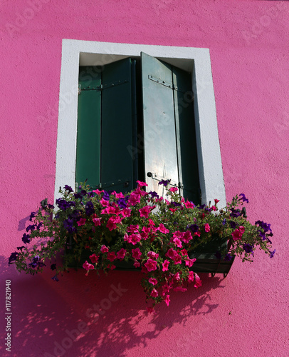 flowered balcony with a window in the house and many flower pots