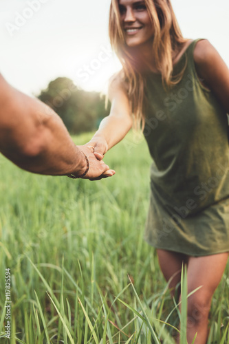 Woman holding hand of her boyfriend in field
