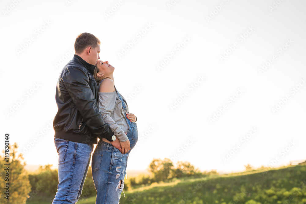 Happy couple awaiting baby, cute pregnant woman with husband enjoying autumn weather, love concept Happy couple awaiting baby, cute pregnant woman with husband enjoying autumn weather, love concept