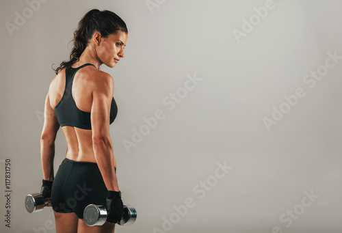Foto Strong muscular young woman holding dumbbells