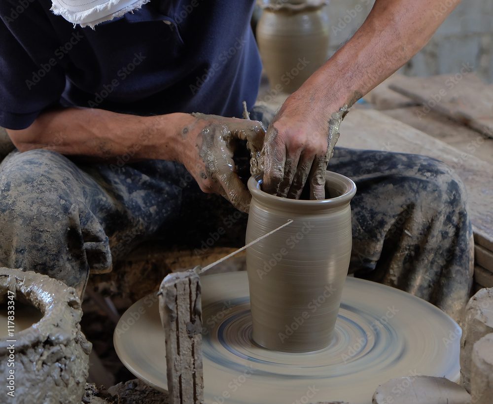 Dirty hands making pottery in clay on wheel