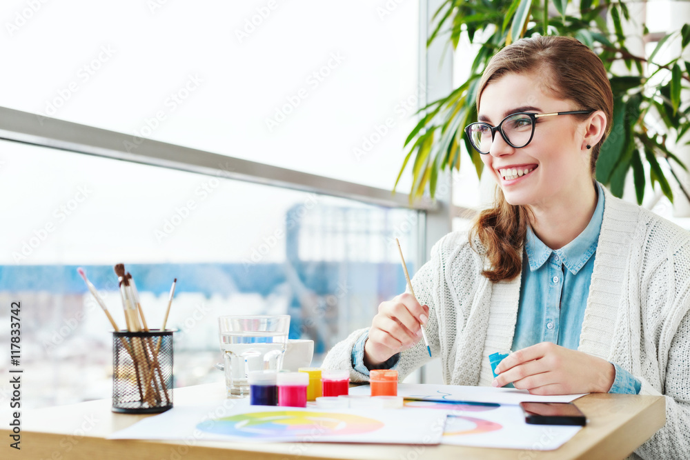 Girl with glasses sitting with colorful paints