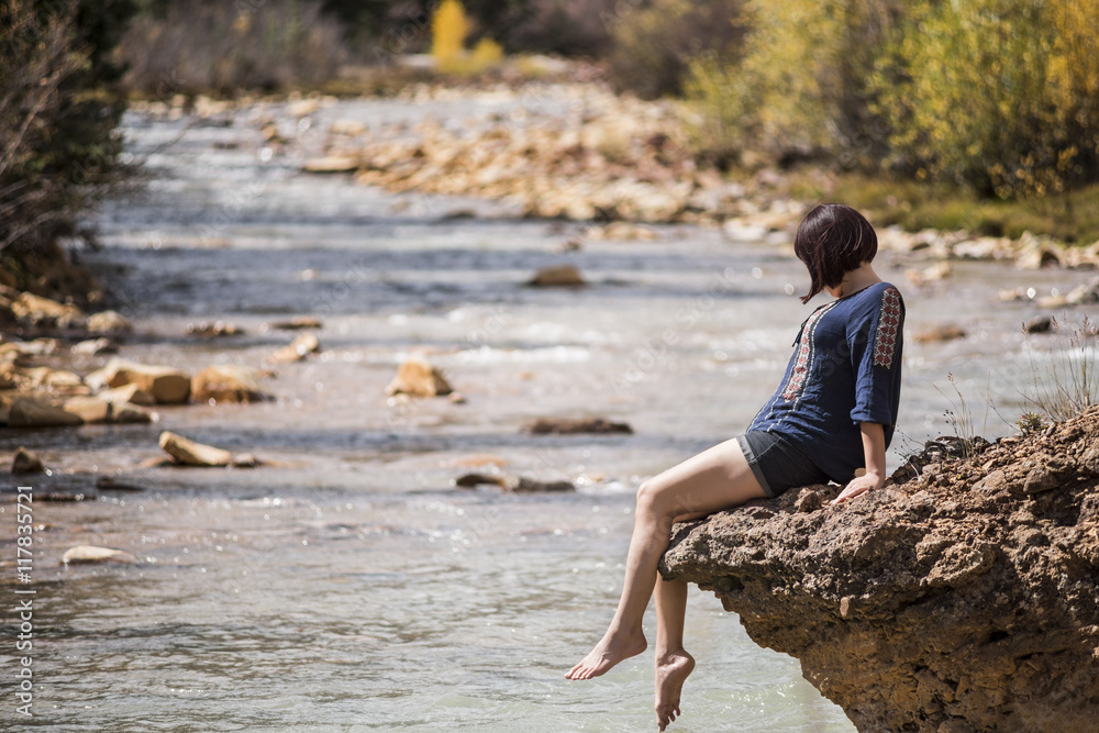 White water Mineral Creek stream in Colorado, USA during the fall with golden aspens and woman on edge dipping feet in water White water Mineral Creek stream in Colorado, USA during the fall with golden aspens and woman on edge dipping feet in water