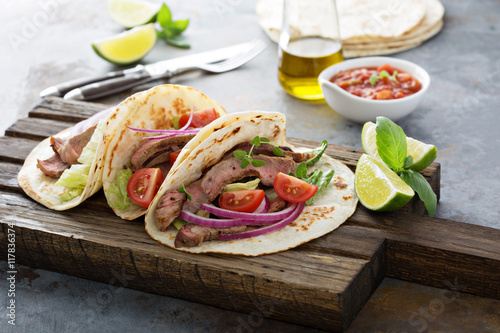 Steak tacos with sliced meet, salad and tomato salsa photo