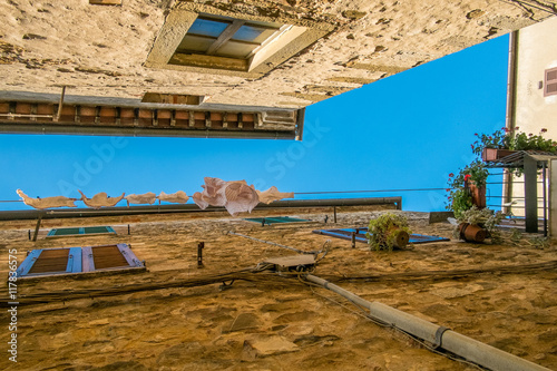 View upwards of washing in narrow street in Montemerano, Tuscany