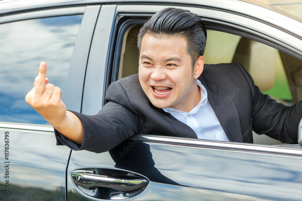 Asian young man driving a car and showing the middle finger Photos