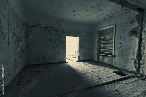 Dark room in an abandoned ruined house. Grunge texture. Tinted photo.