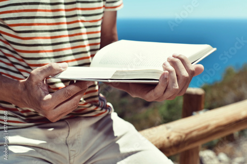 young man reading a book outdoors