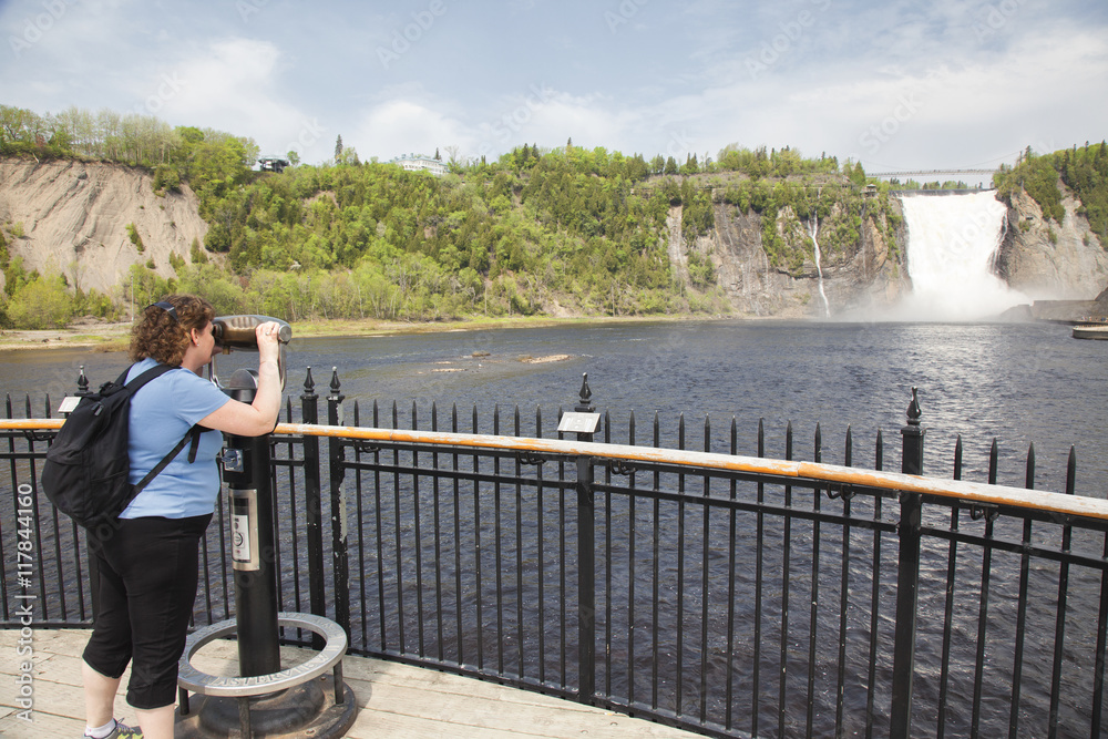 Woman looking through periscope magnifier to view Monmorency Falls in Quebec