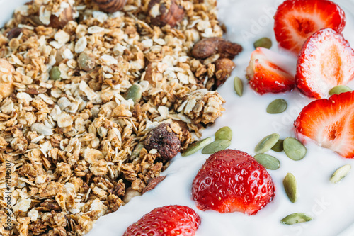 Homemade granola with fresh strawberry over vanilla yogurt. Healthy breakfast