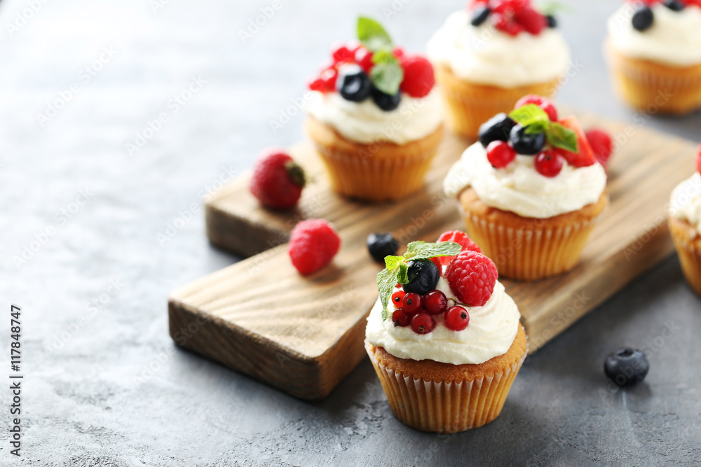 Tasty cupcakes with berries on cutting board Tasty cupcakes with berries on cutting board