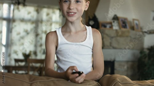 Child watching TV, little girl having fun on the couch, holding remote control