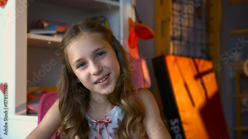 Cute dreamy little girl holding markers searching for ideas while sitting at table