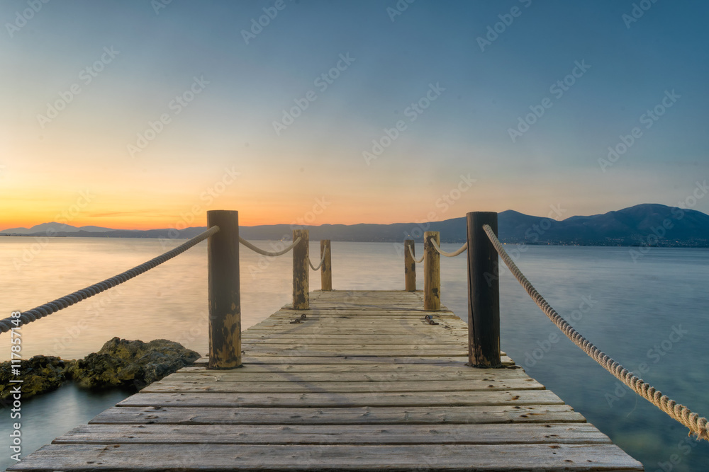 Wooden bridge against the sunset and sea at Oropos in Greece.
