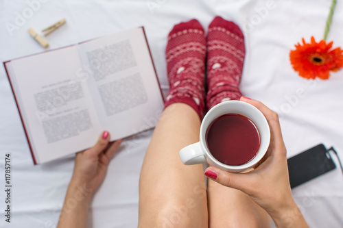 Obraz na plátně Woman reading a book and having cup of tea