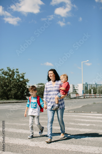 Mother and her children walking to school on a sunny morning