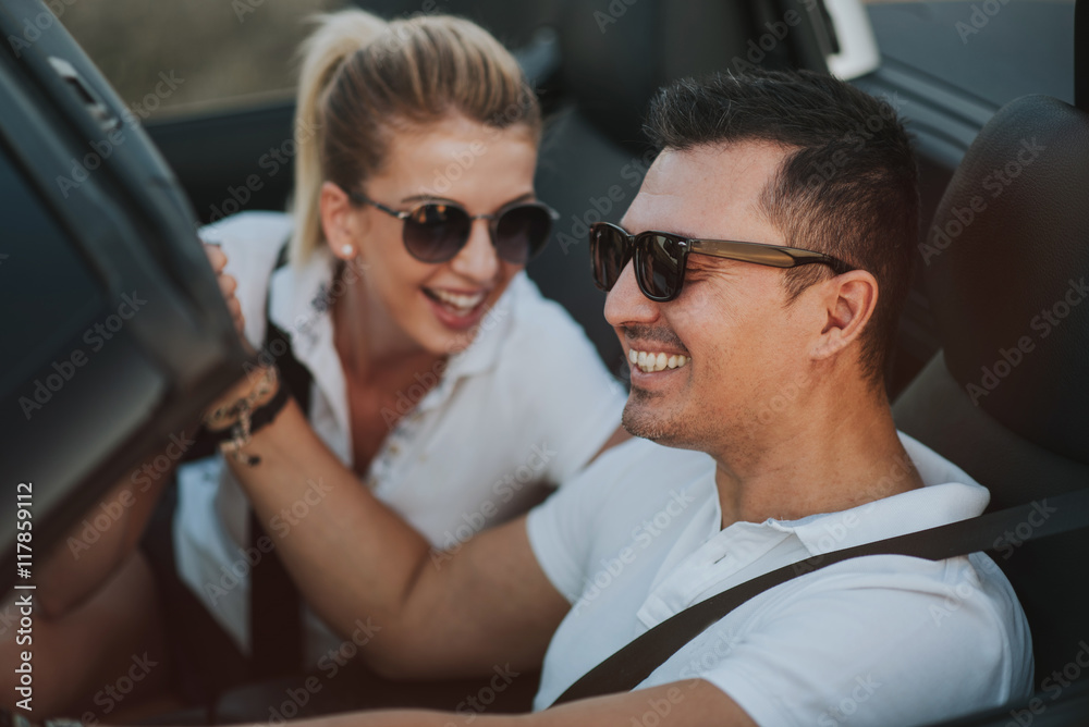 cheerful family couple lovers smiling and cheating to each other driving a cabriolet and searching the location they need by pointing on car gps system cheerful family couple lovers smiling and cheating to each other driving a cabriolet and searching the location they need by pointing on car gps system