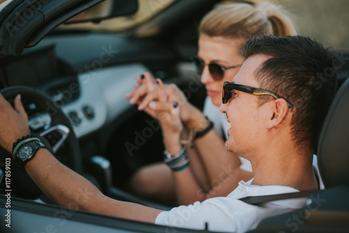 cheerful family couple lovers smiling and cheating to each other driving a cabriolet and searching the location they need by pointing on car gps system © sergiubirca