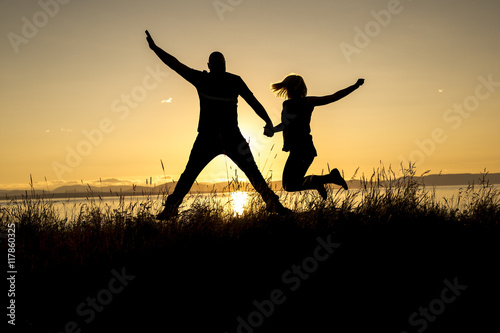 Silhouettes of romantic couple on tropical beach at sunset