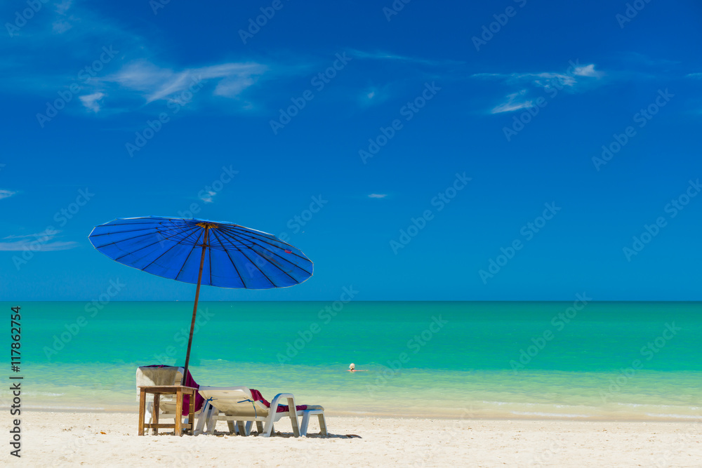 Beach chairs on the sand beach with cloudy blue sky