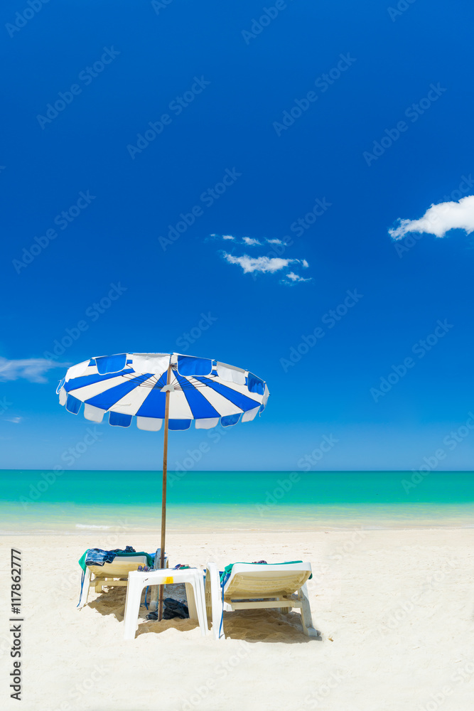 Beach chairs on the sand beach with cloudy blue sky