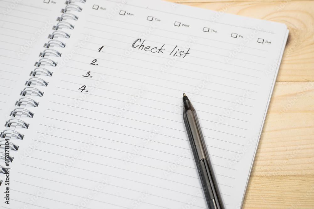 Checklist on notebook page with pen on wood background Checklist on notebook page with pen on wood background