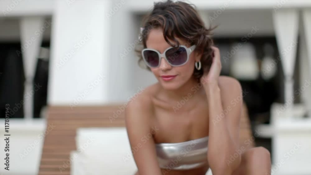 woman relaxes on daybed around pool
