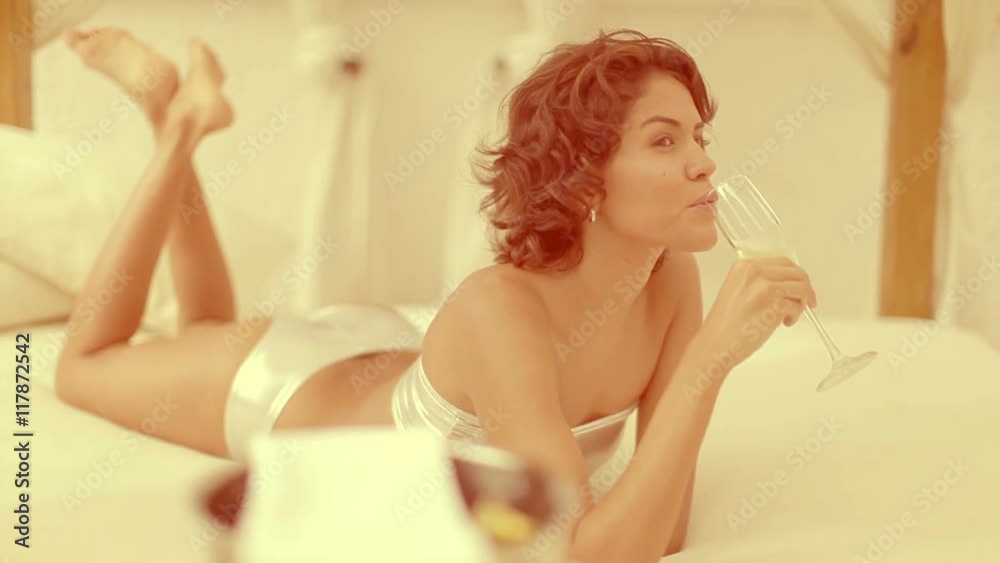 woman drinks champagne on daybed around pool woman drinks champagne on daybed around pool