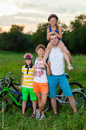 Family on bicycles on the grass field photo