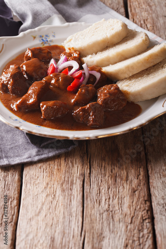 Czech Food: goulash with knedle on the table close-up. vertical
