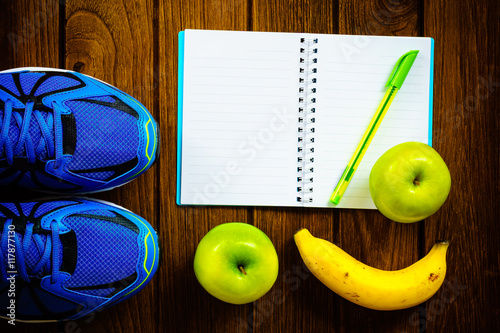 Sport shoes, apples and bananas  on a  wooden background. Sport