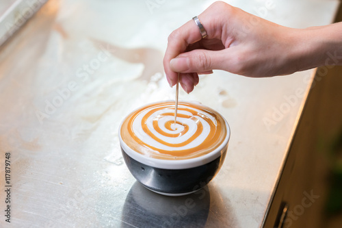 Barista creates a caramell picture in a cup of coffee latte 