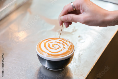 Barista creates a caramell picture in a cup of coffee latte 