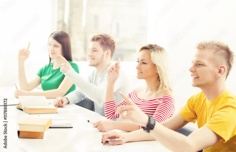 Group of students raising hands. Teenagers study in a classroom Group of students raising hands. Teenagers study in a classroom