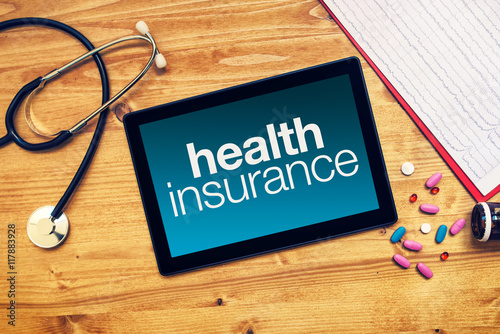 Health insurance title on tablet computer placed on doctors desk