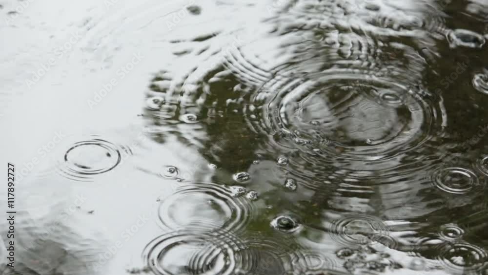 Closeup of rain drops falling in the puddles on the road Closeup of rain drops falling in the puddles on the road
